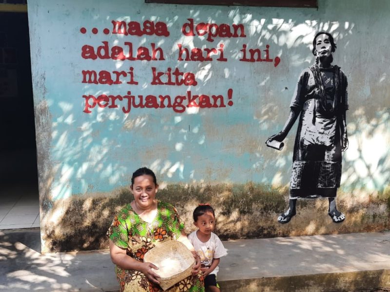 Warga Desa Wadas duduk di depan mural