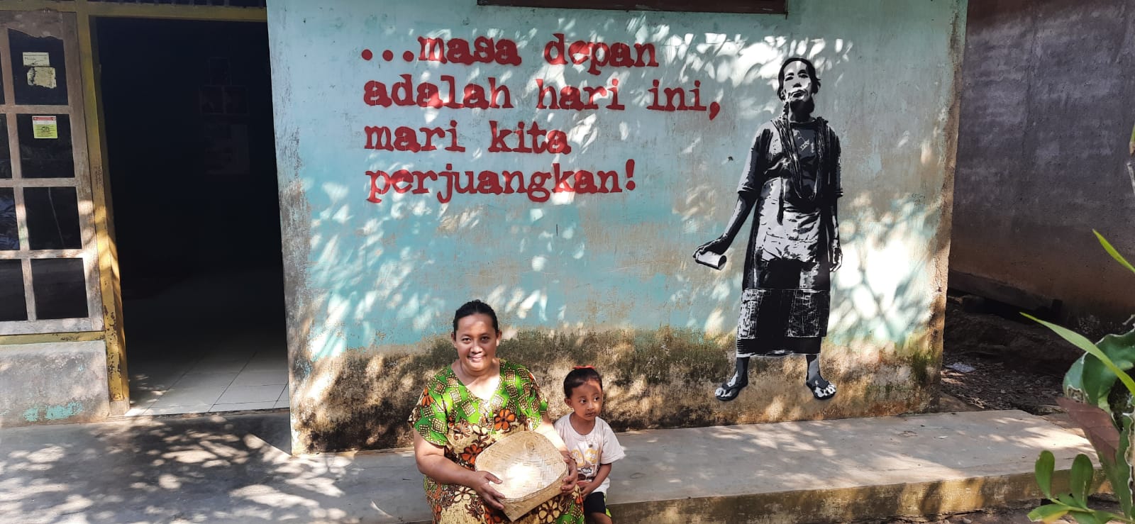 Warga Desa Wadas duduk di depan mural