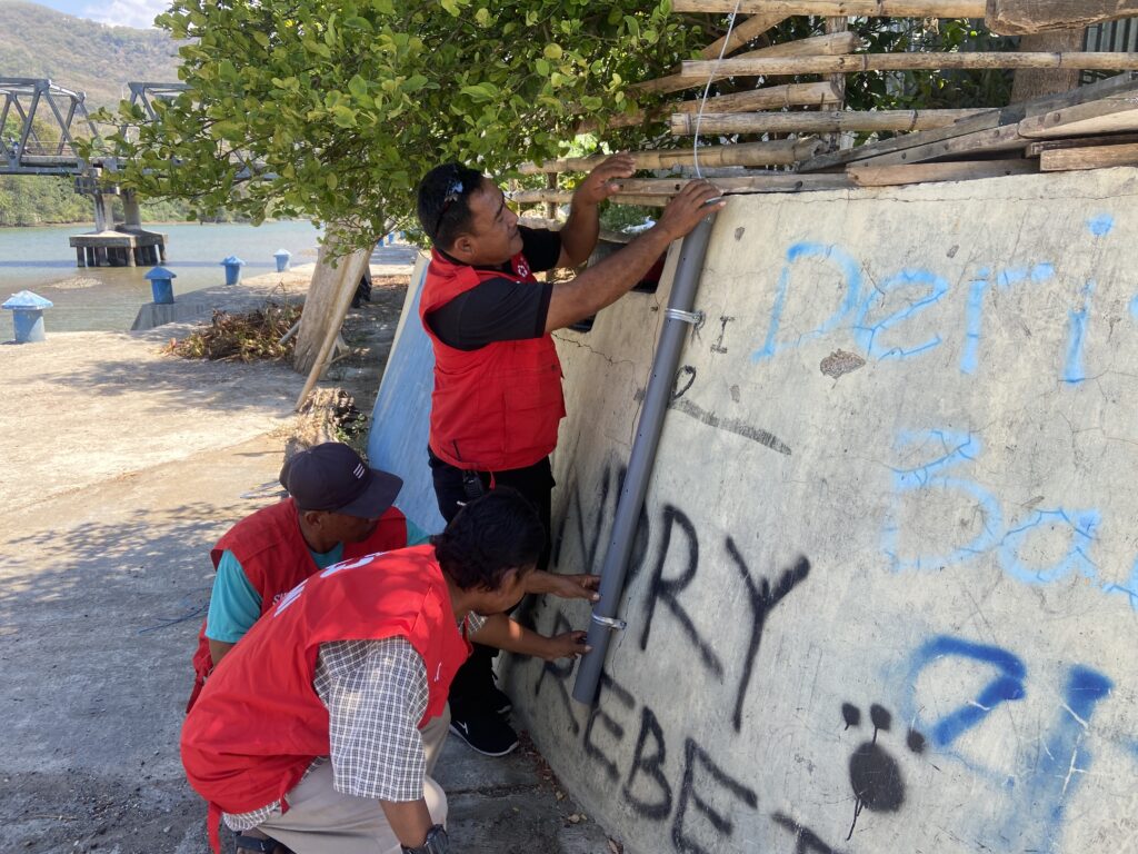 Relawan SIBAT Kelurahan Baru, Kecamatan Reok, Kabupaten Manggarai, NTT menunjukkan cara kerja sensor alat early warning system yang dipasang di pinggir Sungai Wae Pesi. (Foto/Chairul Akhmad)